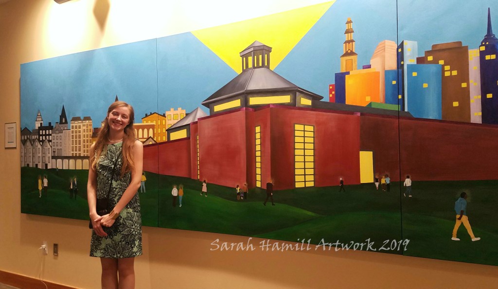 Artist Sarah Hamill standing in front of completed mural for New Brunswick Theological Seminary's 235th Anniversary celebration, installed in its final location at seminary.